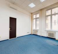 Büros mit blauem Teppichboden, weißen Wänden und großen Fenstern.