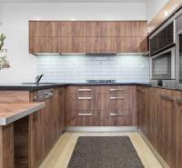 Küche in einer 2-Zimmer-Wohnung mit Holzschränken, weißen Fliesen und einem Boden in Holzoptik.