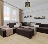 Wohnzimmer in einer 2-Zimmer-Wohnung mit dunklem Sofa, Steckdosen und Boden in Holzoptik.