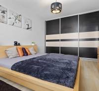 Schlafzimmer in einer 2-Zimmer-Wohnung mit Bett, Schrank und Dekorationen, Boden mit Holzdekor.