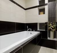 Badezimmer mit Badewanne und Keramikfliesen in Schwarz-Weiß-Kombination in einer 2-Zimmer-Wohnung.