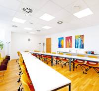 Innenraum eines Büros mit Holzboden, gelbe Stühle und moderne Kunstwerke.