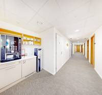 Büro mit Kaffeemaschine und Wasserspender, helle Wände und Teppich.