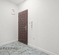 Ein weißer Flur mit dunklen Türen und Fliesen in einer 2-Zimmer-Wohnung.