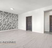 Wohnzimmer mit Holzboden und geometrischer Wand in einer Zweizimmerwohnung.