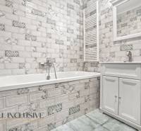 Badezimmer in der Ausführung einer 2-Zimmer-Wohnung mit weißen Fliesen und einer Badewanne.