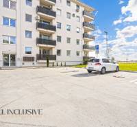 Parkplatz vor dem Wohnhaus in Panónsky háj in Dunajská Streda, mit Autos und einer Rasenfläche.