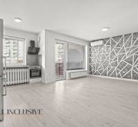 Küche und Wohnzimmer in einer Zweizimmerwohnung mit Holzboden und geometrischer Wand.