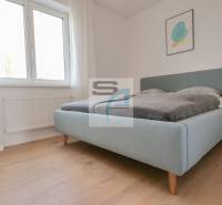 Schlafzimmer in einer 2-Zimmer-Wohnung, helles Bett, Boden mit Holzdekor, einfache Dekoration.