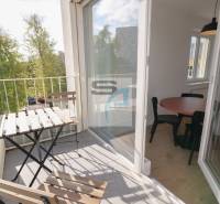 Balkon mit Sitzgelegenheit, Blick ins Grüne und Glastüren in die 2-Zimmer-Wohnung.