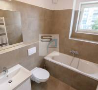 Badezimmer in einer 2-Zimmer-Wohnung mit Badewanne, Waschbecken, Spiegel und Fenster.