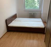 Schlafzimmer in einer 2-Zimmer-Wohnung mit einem Bett und einem Boden in Holzoptik.