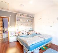 Kinderzimmer in einer Zweizimmerwohnung mit Bett, Regalen und Boden in Holzoptik.