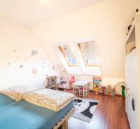 Kinderzimmer in einer 2-Zimmer-Wohnung mit Dachfenstern, Möbeln und Spielzeug.