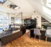 Wohnzimmer mit Küche in einer 2-Zimmer-Wohnung mit Holzboden und bequemer Couch.