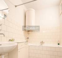 Badezimmer im Einfamilienhaus mit Badewanne, Waschbecken und Boden mit Holzdekor.