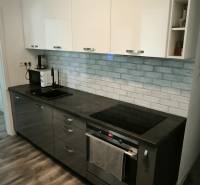 Küche in einer 3-Zimmer-Wohnung mit dunklen Schränken und einem Boden in Holzoptik.