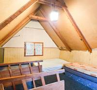 Ein Dachzimmer in einer Hütte mit Dachbalken und einfacher Einrichtung.