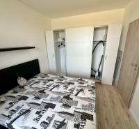 Schlafzimmer mit Einbauschrank, Bett und Boden mit Holzdekor in einer 2-Zimmer-Wohnung.