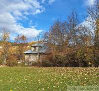 Ein Einfamilienhaus in Liptovské Beharovce, umgeben von herbstlichen Bäumen und einer grünen Wiese.