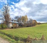 Ein Einfamilienhaus in Liptovské Beharovce, umgeben von Natur und herbstlichen Bäumen am Rande einer Wiese.