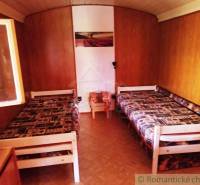 Innenraum einer Holzhütte mit zwei Betten und einem Boden in Holzoptik.