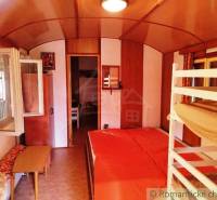 Das Innere einer Hütte mit einem Etagenbett, einem Boden in Holzoptik und einem offenen Fenster.