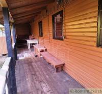 Eine Hütte in Dudince mit einer Veranda, einem Boden in Holzoptik und einer Bank.