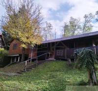 Ein Ferienhaus in Dudince, umgeben von Natur, mit Terrasse und Bäumen im Garten.