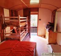 Innenraum einer Hütte mit vier Betten und einem hellen Ausblick auf die Terrasse.