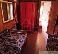 Das Innere der Hütte mit zwei Betten, einem roten Schrank und einem Teppich mit geometrischem Muster.