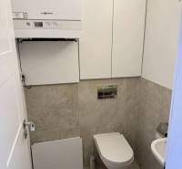 Toilette in einer 3-Zimmer-Wohnung mit einem modernen Wandkessel und beigefarbenen Fliesen.