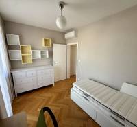 Ein Zimmer in einer 3-Zimmer-Wohnung mit hellen Möbeln und einem Boden in Holzoptik.