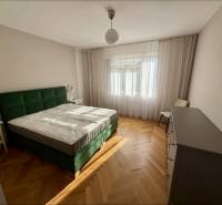 Schlafzimmer mit grünem Bett, Boden mit Holzdekor, blickdichte Vorhänge, 3-Zimmer-Wohnung.