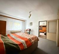 Schlafzimmer im Einfamilienhaus mit hellem Teppich, Fenster und Bett mit Decke.