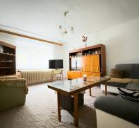 Wohnzimmer in einem Einfamilienhaus mit Sofas, Schränken und einem Tisch, Teppich auf dem Boden.