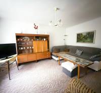 Wohnzimmer in einem Einfamilienhaus mit Sofa, Fernseher und Holzwohnwand.