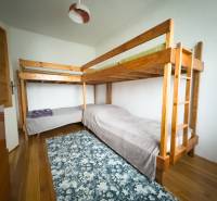 Etagenbett in einem Einfamilienhaus mit Holzboden und gemustertem Teppich.