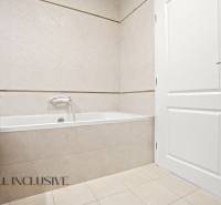 Badezimmer mit Badewanne, weißen Türen und hellen Fliesen in einer 2-Zimmer-Wohnung.