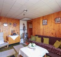 Ein Zimmer mit Sofa, Sessel, Tisch und Holzvertäfelung bietet einen gemütlichen Raum in den Gärten.