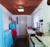 Küchenecke in den Gärten mit Vorhängen, Holzdecke und einfacher Ausstattung.