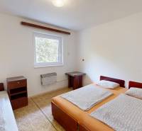 Ein Schlafzimmer in einer Hütte mit drei Betten, einem Nachttisch und einem Fenster mit Aussicht.