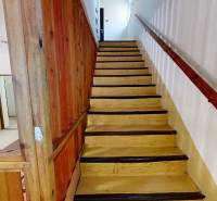 Eine Holztreppe mit einem Holzgeländer und einer Wand im Inneren einer Hütte.