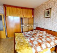 Schlafzimmer in einer 3-Zimmer-Wohnung mit dekorativer Tapete und Holzmöbeln.