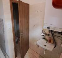 Badezimmer in Geschäftsräumen mit Waschbecken, Boiler und Tür zur Toilette.