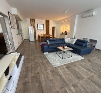 Wohnzimmer mit großem Sofa und Fernseher in einer 2-Zimmer-Wohnung, Boden mit Holzdekor.