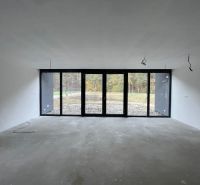 Priestranná miestnosť s veľkými oknami v rodinnom dome, výhľad do záhrady.