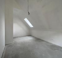 Ein Dachgeschosszimmer in einem Einfamilienhaus mit einem Fenster in der Decke und Steckdosen.