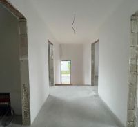 Das Innere eines Einfamilienhauses mit weißen Wänden und offenen Türen zu einem weiteren Raum.