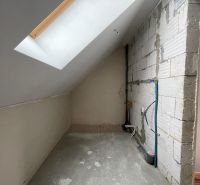 Dachboden eines Einfamilienhauses mit Betonboden und Dachfenster.